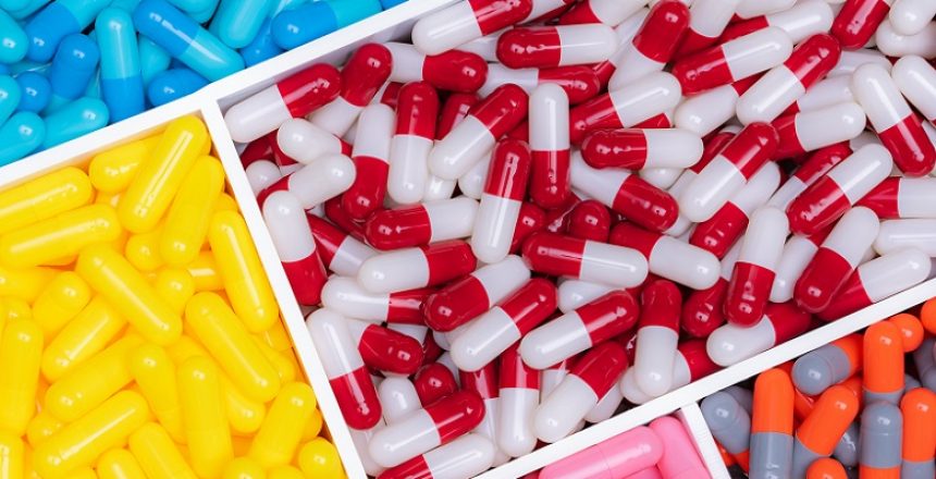 Top view of colorful capsule pills in plastic tray. Pharmaceutical industry. Healthcare and medicine. Drug production. Pharmaceutics concept. Vitamins and supplements capsules. Bright color capsule.