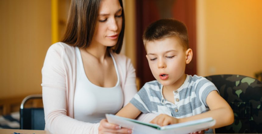 A young mother is doing homework with her son at home. Parents and training