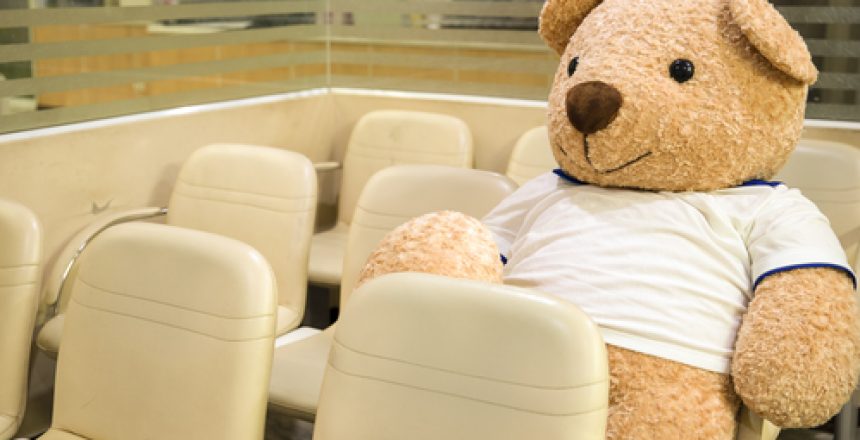 a life size stuffed toy bear sitting at a nonspecific waiting area