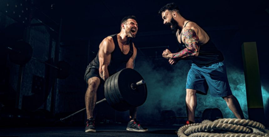 Two muscular bearded tattoed athletes training, one lift heavy weight bar when other is motivating. Scream. Working hard. Exercise for the muscles of the back